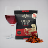 A 30g pack of Made For Drink's Chorizo Thins standing in front of a glass of Rioja wine with a small pile of chorizo thins in the foreground.