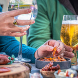 A festive table spread with a gin and tonic, glass of beer and bowl of chorizo thins