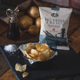 A 40 g pack of Made For Drink's Malt Vinegar & Sea Salt flavoured English Heritage potato crisps, with a bowl of crisps in the foreground and a small jug of malt vinegar in the background.
