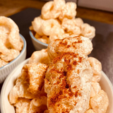 A close up of 3 bowls of Made For Drink's crunchy Iberian Pork Chicharrónes. The closest one topped with a dusting of smoked paprika.