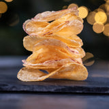 Close up of a stack of Made For Drink Dorset Sea Salt potato crisps on a slate board.